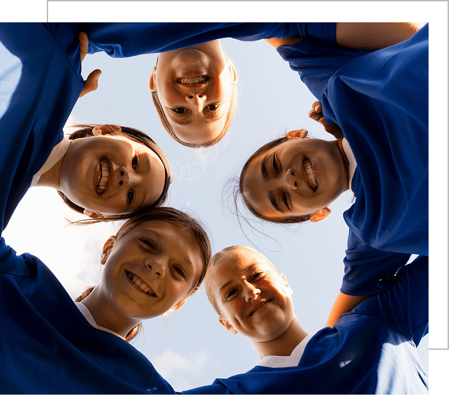 Smiling kids in blue shirts looking down in a circle