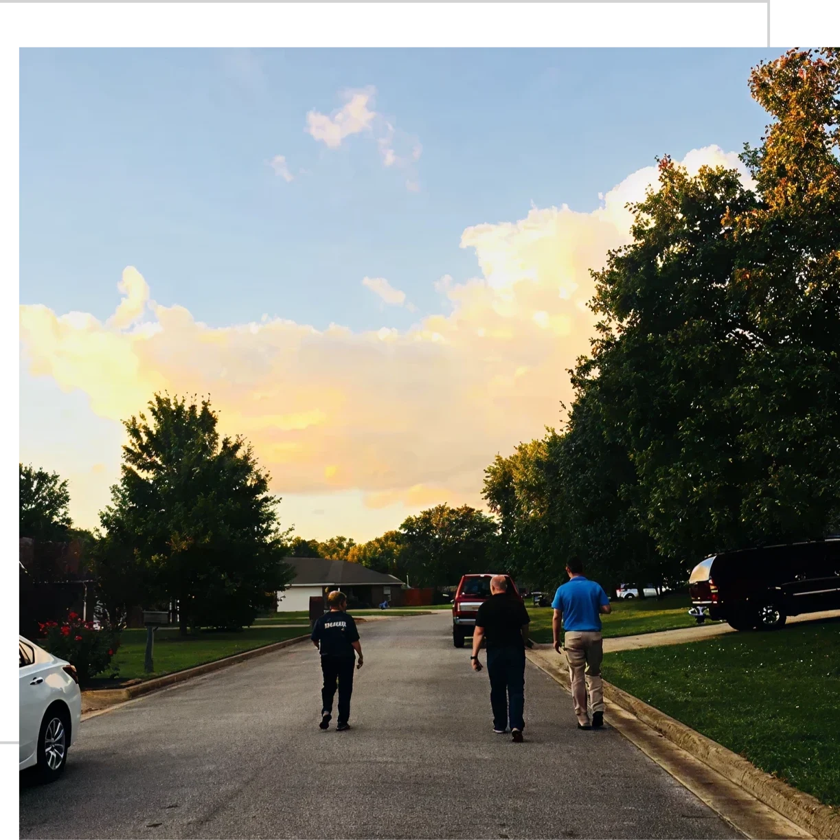 People walking down suburban street at sunset.